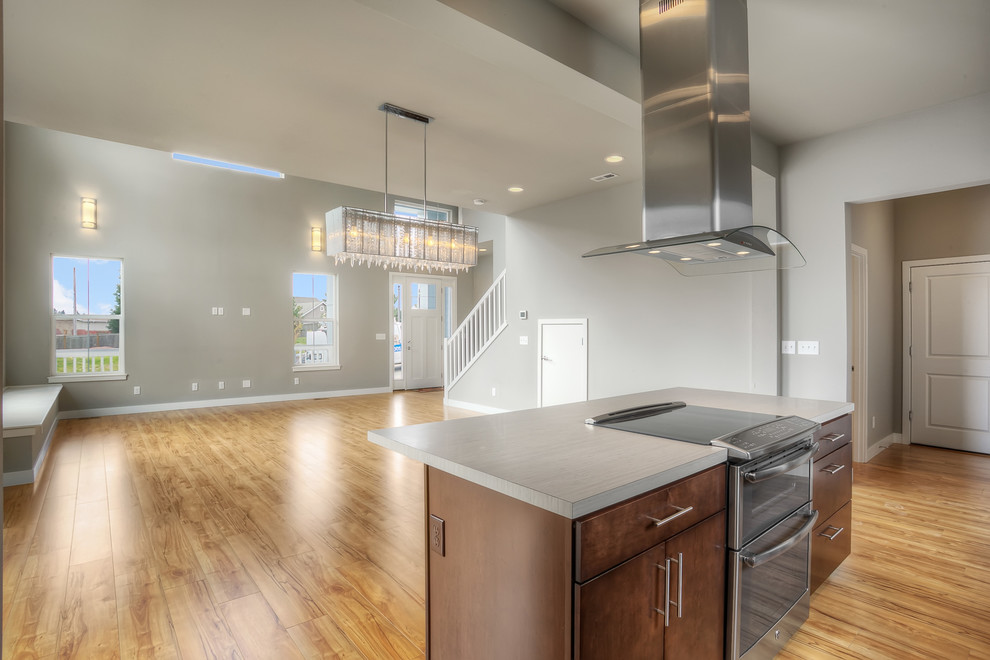 Transitional galley open concept kitchen photo in Seattle with a drop-in sink, flat-panel cabinets, brown cabinets, laminate countertops, beige backsplash, ceramic backsplash, stainless steel appliances, gray walls and an island