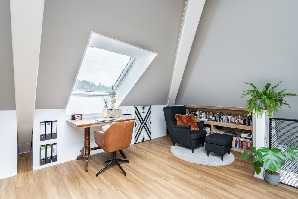 На фото: большое рабочее место в современном стиле с серыми стенами, светлым паркетным полом, отдельно стоящим рабочим столом и коричневым полом