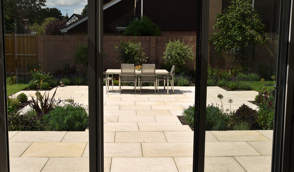 Design ideas for a contemporary back patio in Surrey with natural stone paving.