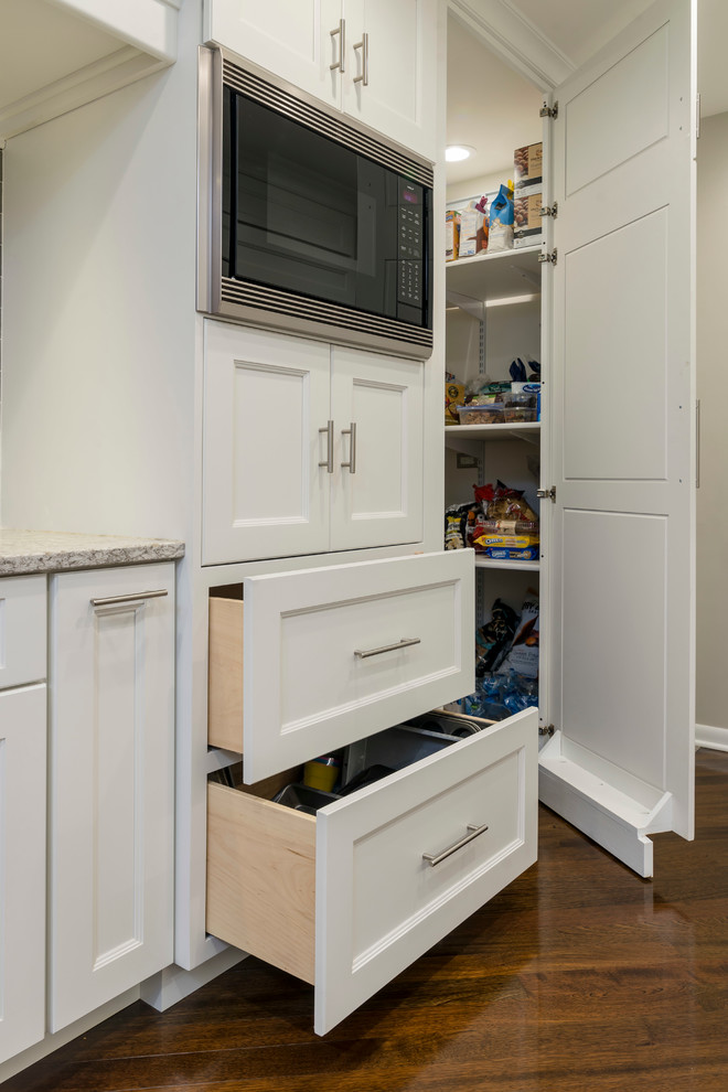 Inspiration for a mid-sized transitional galley medium tone wood floor home design remodel in Chicago with an undermount sink, flat-panel cabinets, white cabinets, quartz countertops, beige backsplash, glass tile backsplash, paneled appliances and a peninsula
