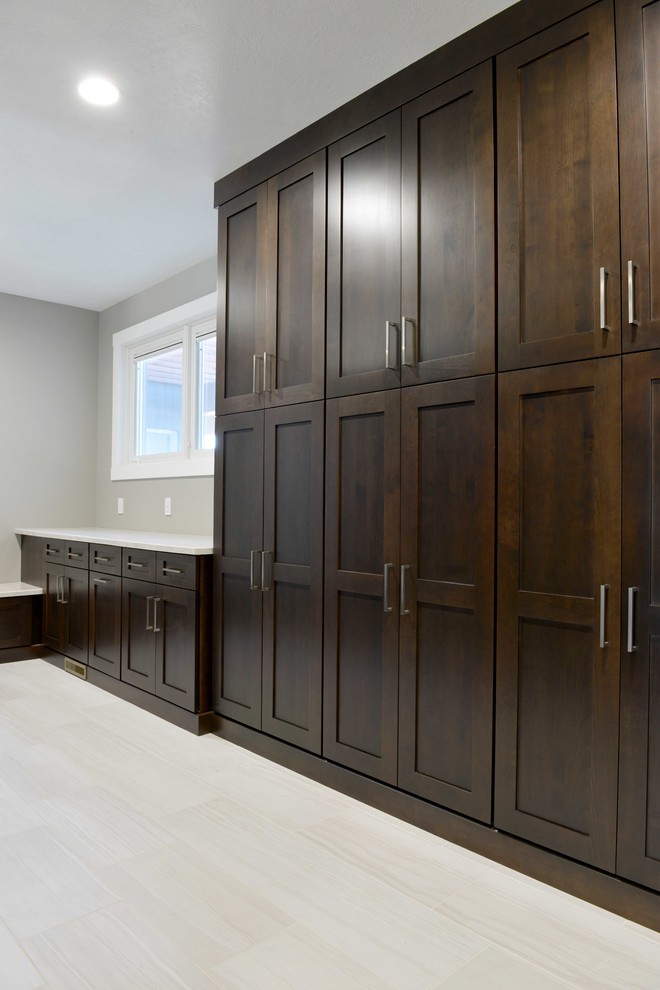 Design ideas for a mid-sized transitional u-shaped utility room in Other with shaker cabinets, dark wood cabinets, quartzite benchtops, grey walls, laminate floors and a side-by-side washer and dryer.