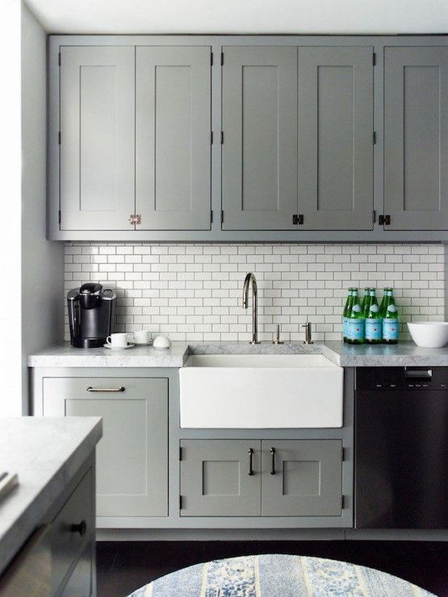 Offene Klassische Küche in grau-weiß mit integriertem Waschbecken, Kassettenfronten, grauen Schränken, Küchenrückwand in Weiß, schwarzen Elektrogeräten, dunklem Holzboden, schwarzem Boden und weißer Arbeitsplatte in Madrid