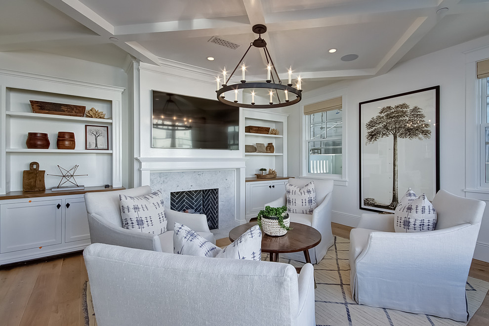 Photo of a beach style living room in Orange County with white walls, light hardwood floors, a standard fireplace, a stone fireplace surround and a wall-mounted tv.
