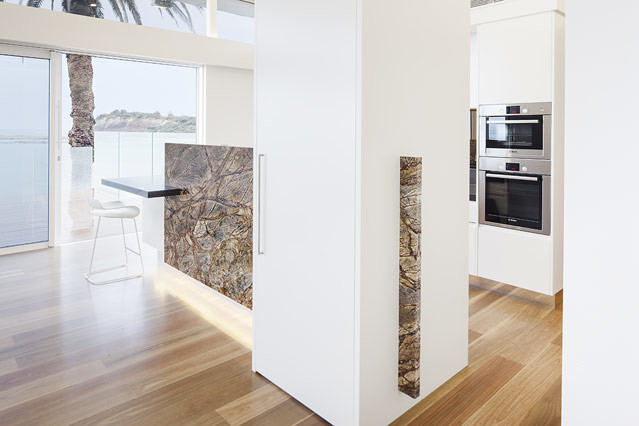 This is an example of a beach style open plan kitchen in Sydney with stainless steel appliances.