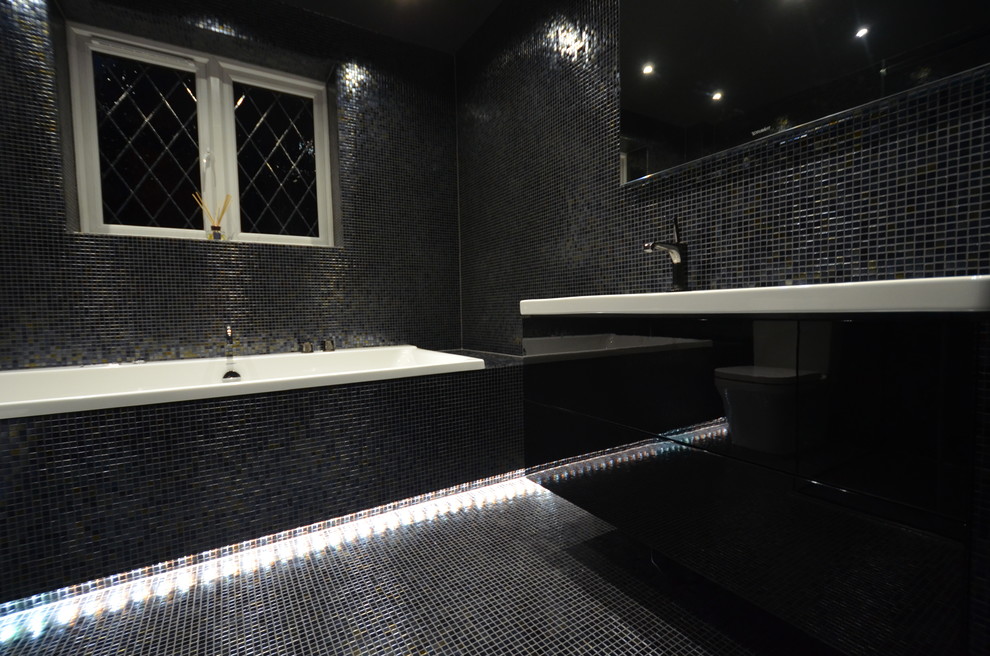 Mid-sized contemporary master bathroom in London with flat-panel cabinets, black cabinets, a drop-in tub, a corner shower, a bidet, black tile, mosaic tile, black walls, brick floors, a console sink and engineered quartz benchtops.