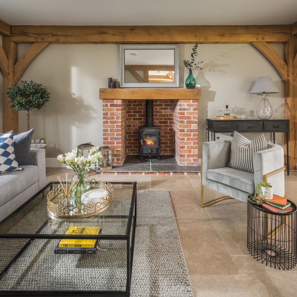 Photo of a country living room in West Midlands with grey walls, a wood stove, a brick fireplace surround, beige floor and exposed beam.
