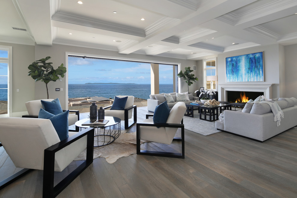This is an example of a beach style open concept living room in Orange County with grey walls, medium hardwood floors and a standard fireplace.