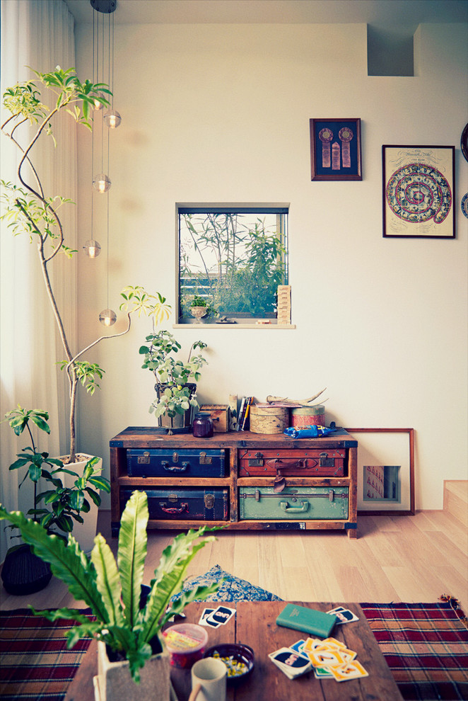 This is an example of a small country living room in Tokyo with white walls and light hardwood floors.