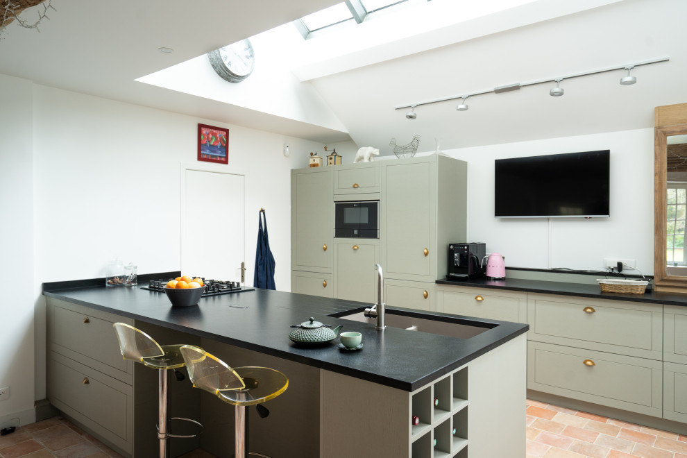 Design ideas for an expansive midcentury galley open plan kitchen in Other with an integrated sink, flat-panel cabinets, green cabinets, granite benchtops, black splashback, granite splashback, panelled appliances, cement tiles, with island, pink floor and black benchtop.