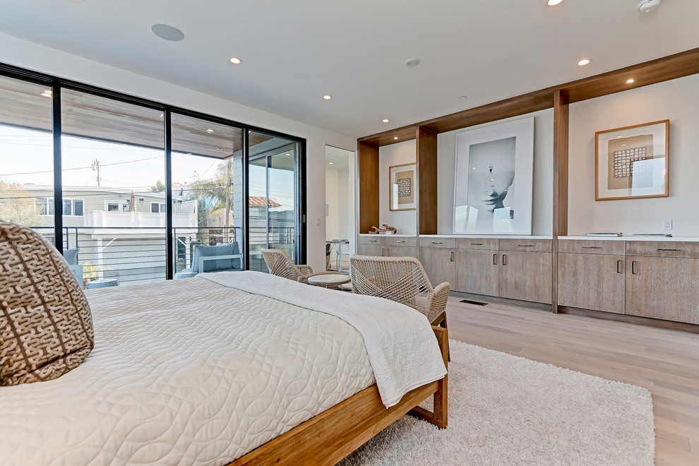 This is an example of a mid-sized beach style master bedroom in Los Angeles with beige walls and light hardwood floors.