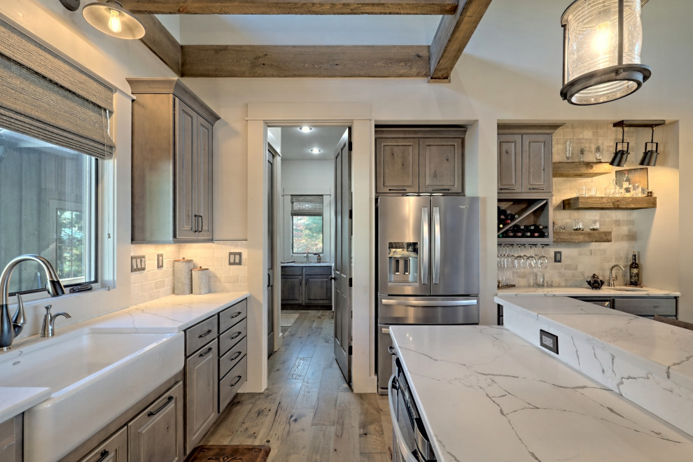 Inspiration for a small country u-shaped open plan kitchen in Atlanta with a farmhouse sink, raised-panel cabinets, light wood cabinets, quartz benchtops, white splashback, travertine splashback, stainless steel appliances, a peninsula, brown floor and white benchtop.