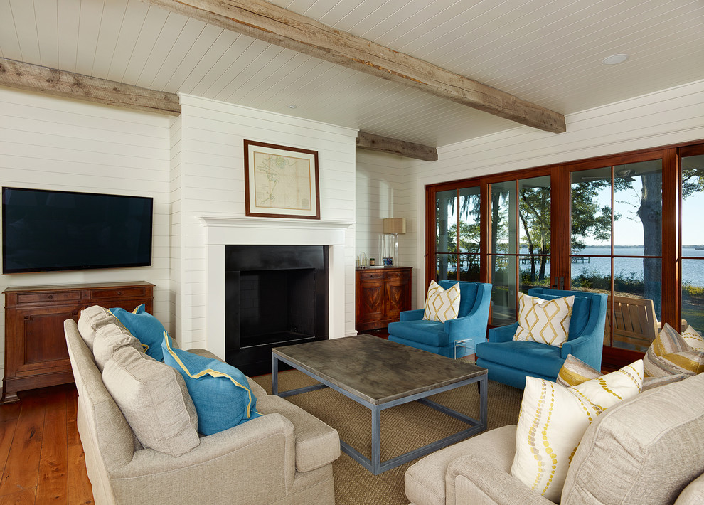 Photo of a beach style living room in Charleston with white walls, a standard fireplace and a wall-mounted tv.