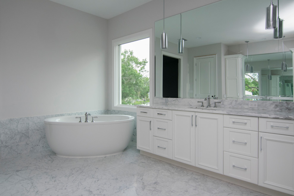 Inspiration for a large transitional master bathroom in Tampa with recessed-panel cabinets, white cabinets, a freestanding tub, gray tile, white tile, stone slab, white walls, marble floors, a wall-mount sink, marble benchtops, grey floor, a corner shower and a hinged shower door.
