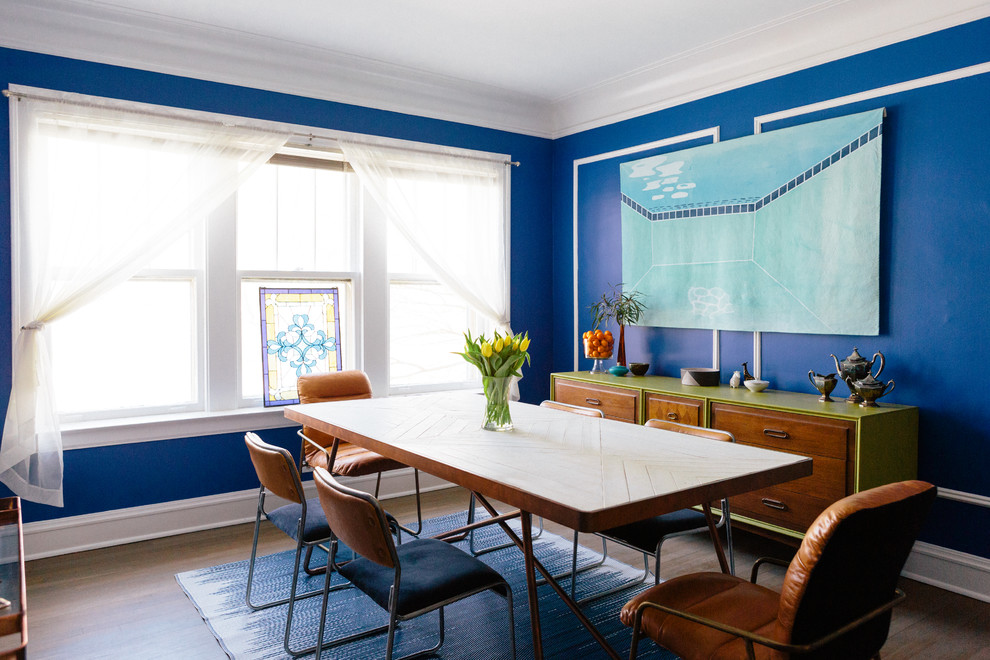 Eclectic separate dining room in Chicago with blue walls, medium hardwood floors and brown floor.