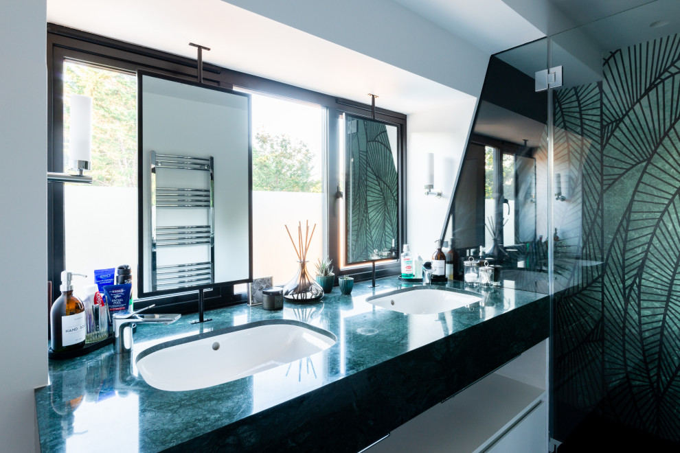 Photo of a medium sized contemporary ensuite bathroom in London with flat-panel cabinets, white cabinets, a walk-in shower, a wall mounted toilet, white walls, ceramic flooring, a built-in sink, marble worktops, black floors, a sliding door, green worktops, a feature wall, double sinks and a floating vanity unit.