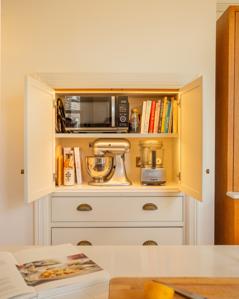 Design ideas for a large traditional l-shaped kitchen/diner with beaded cabinets, white cabinets, engineered quartz splashback, medium hardwood flooring, an island, brown floors and a chimney breast.
