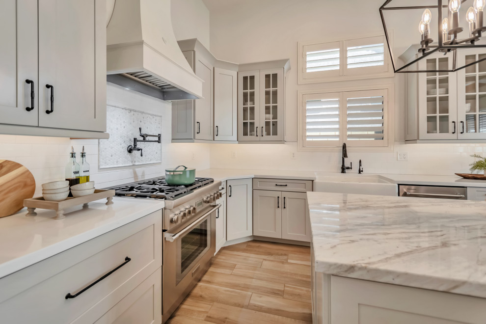 Inspiration for a large transitional u-shaped porcelain tile, brown floor and exposed beam kitchen remodel in Phoenix with a farmhouse sink, shaker cabinets, gray cabinets, quartzite countertops, white backsplash, porcelain backsplash, stainless steel appliances, an island and white countertops