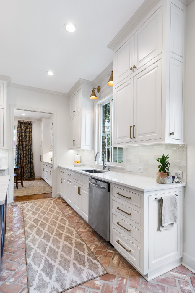 Exempel på ett stort klassiskt grå grått kök, med en undermonterad diskho, luckor med upphöjd panel, vita skåp, bänkskiva i kvartsit, grått stänkskydd, stänkskydd i keramik, rostfria vitvaror, tegelgolv, en köksö och rött golv