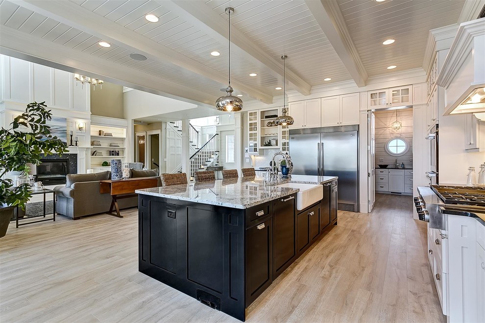 Inspiration for a large traditional l-shaped open plan kitchen in Boise with a farmhouse sink, shaker cabinets, white cabinets, granite benchtops, white splashback, ceramic splashback, stainless steel appliances, light hardwood floors and with island.