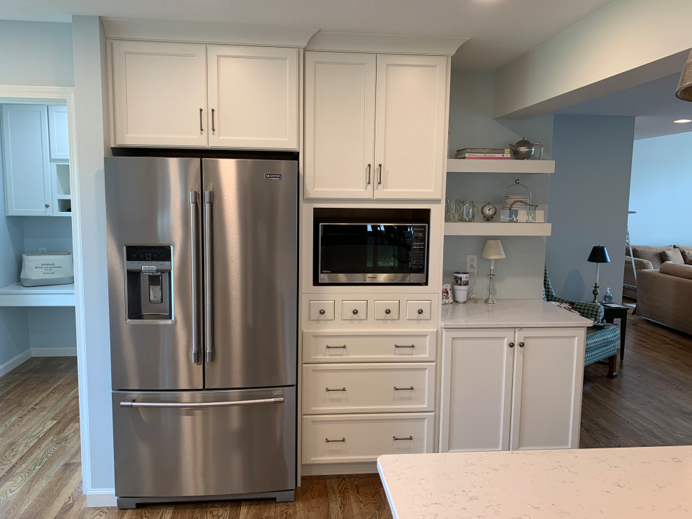 Open concept kitchen - large transitional u-shaped medium tone wood floor and brown floor open concept kitchen idea with an undermount sink, recessed-panel cabinets, white cabinets, quartz countertops, white backsplash, stainless steel appliances, an island and white countertops