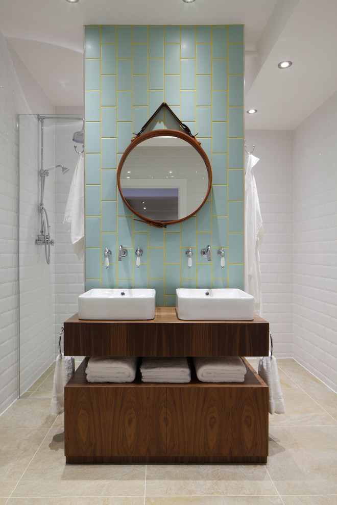 Photo of a mid-sized industrial bathroom in London with blue tile, a vessel sink, wood benchtops, a corner shower, subway tile, white walls and brown benchtops.