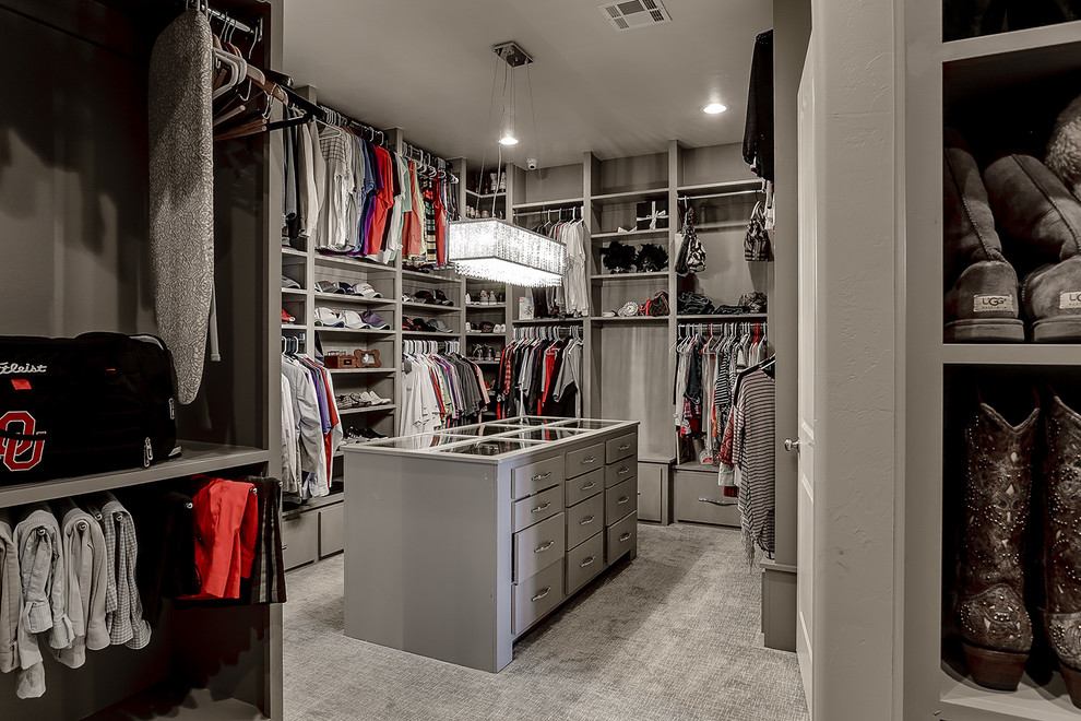 This is an example of a large contemporary gender-neutral walk-in wardrobe in Oklahoma City with flat-panel cabinets, grey cabinets and carpet.