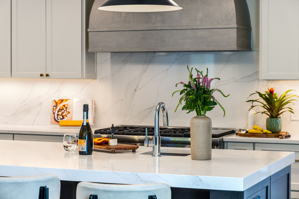 Kitchen - mid-sized transitional medium tone wood floor kitchen idea in DC Metro with a single-bowl sink, flat-panel cabinets, quartz countertops, white backsplash, quartz backsplash, stainless steel appliances, an island and white countertops