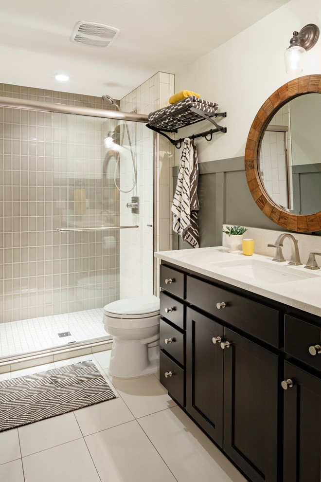 This is an example of a mid-sized transitional 3/4 bathroom in Portland with shaker cabinets, black cabinets, an alcove shower, a one-piece toilet, gray tile, ceramic tile, white walls, ceramic floors, an undermount sink and granite benchtops.