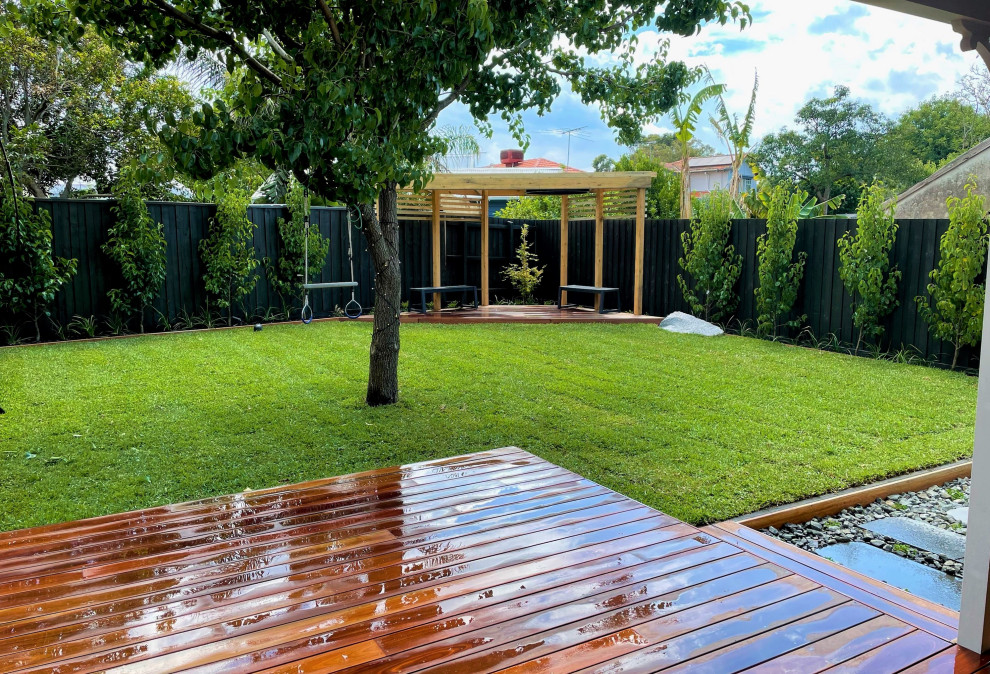 This is an example of a mid-sized asian backyard full sun formal garden in Melbourne with decking and a wood fence.