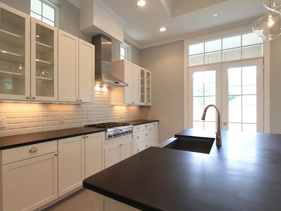 Large arts and crafts l-shaped kitchen in Houston with a farmhouse sink, shaker cabinets, white cabinets, white splashback, subway tile splashback, stainless steel appliances, porcelain floors and with island.