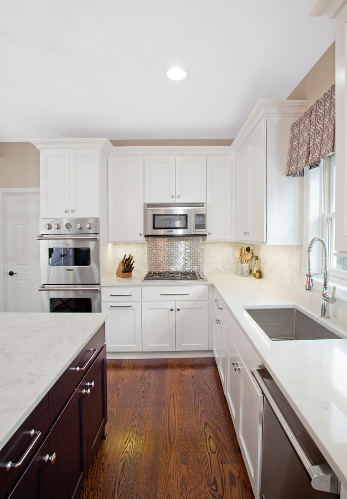 Photo of a mid-sized transitional l-shaped eat-in kitchen in Philadelphia with a single-bowl sink, shaker cabinets, white cabinets, marble benchtops, white splashback, stone tile splashback, stainless steel appliances, dark hardwood floors and with island.