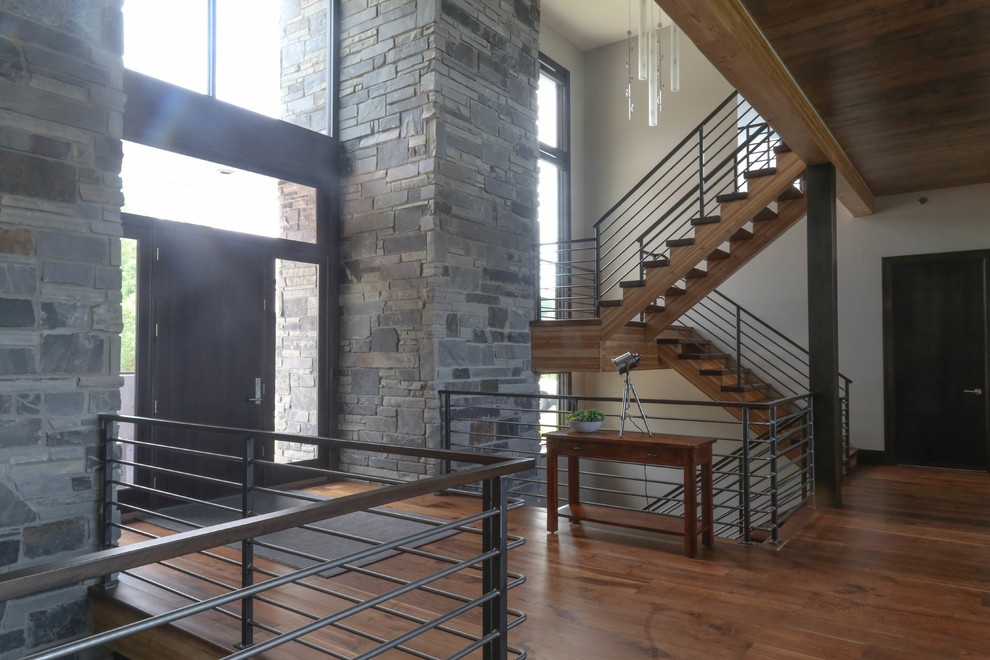 Example of a large medium tone wood floor and brown floor front door design with white walls and a dark wood front door