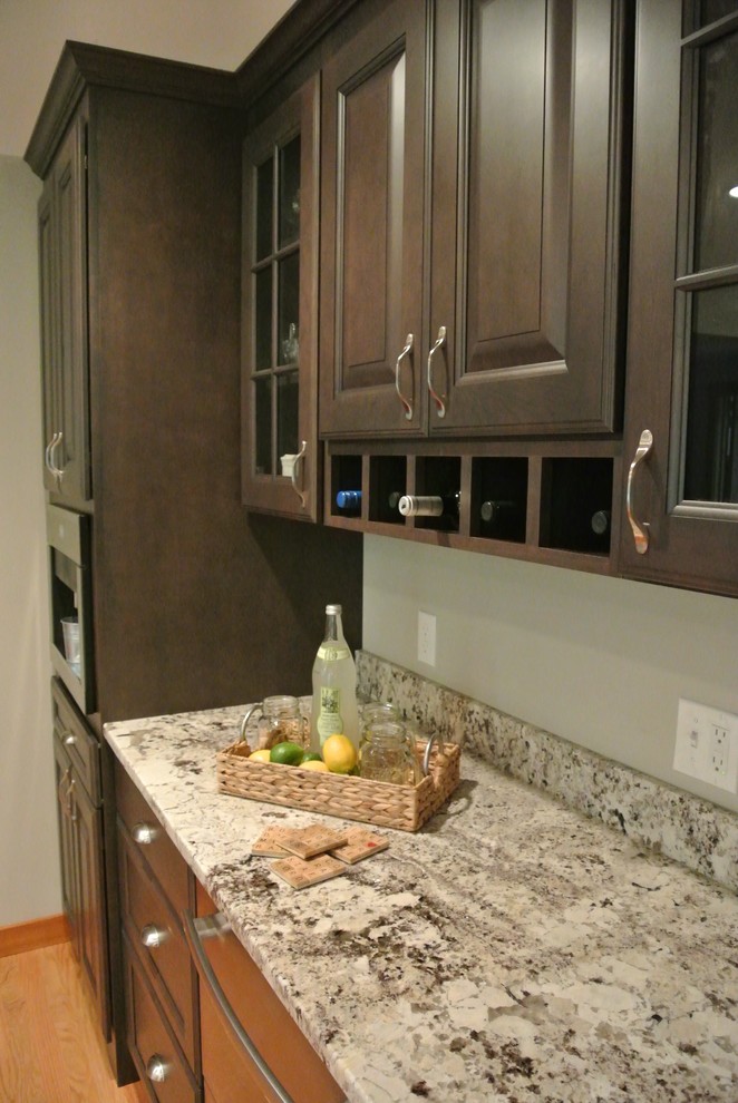 Large transitional l-shaped light wood floor eat-in kitchen photo in Boston with a farmhouse sink, shaker cabinets, gray cabinets, granite countertops, white backsplash, ceramic backsplash, stainless steel appliances, an island and gray countertops