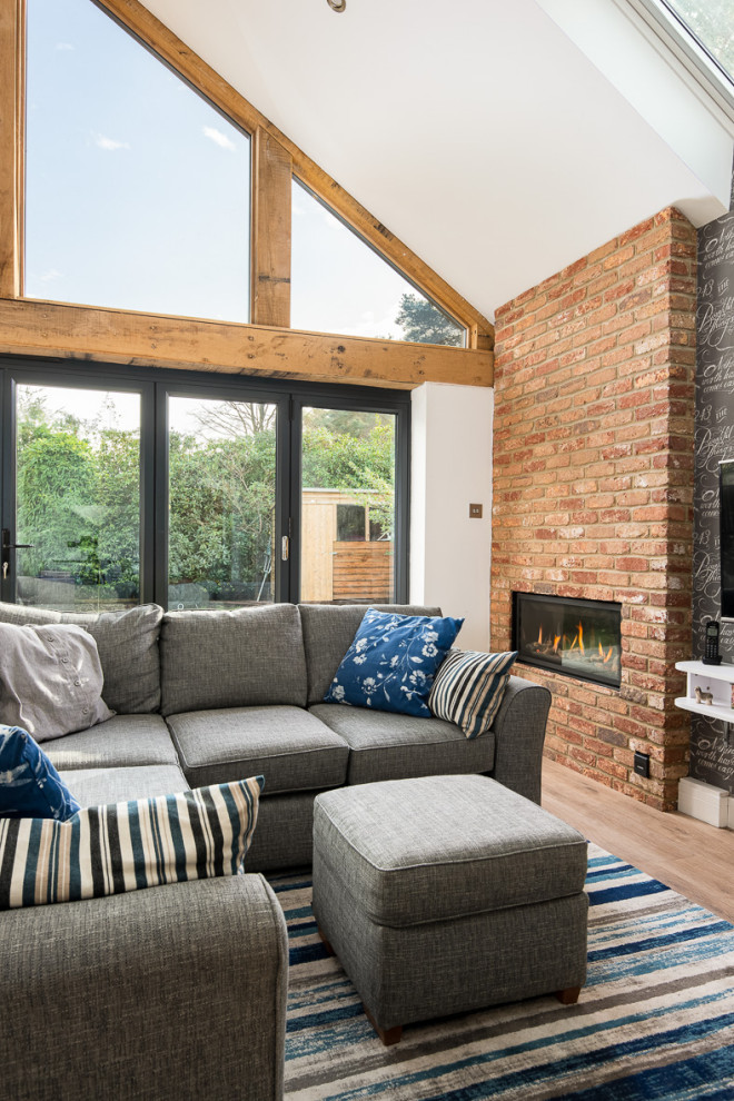 Design ideas for a small traditional open concept living room in Hampshire with white walls, a ribbon fireplace and a brick fireplace surround.