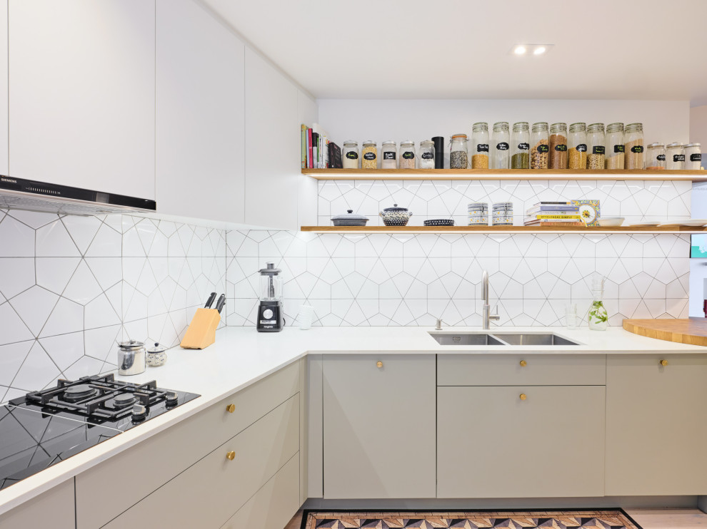 Mid-sized contemporary l-shaped separate kitchen in London with an undermount sink, flat-panel cabinets, grey cabinets, solid surface benchtops, white splashback, ceramic splashback, black appliances, light hardwood floors, no island and yellow benchtop.