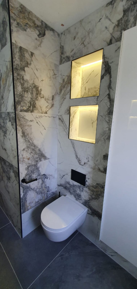 Inredning av ett modernt mellanstort vit vitt en-suite badrum, med släta luckor, vita skåp, en öppen dusch, en vägghängd toalettstol, svart och vit kakel, marmorkakel, flerfärgade väggar, klinkergolv i porslin, ett fristående handfat, laminatbänkskiva, svart golv och med dusch som är öppen