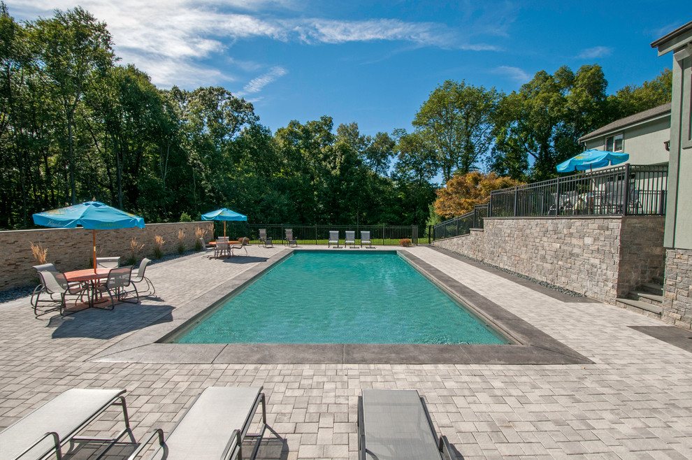 Backyard stamped concrete and rectangular pool photo in Boston