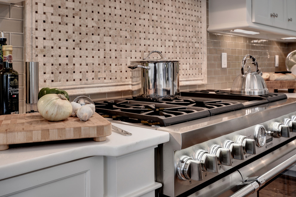 Inspiration for a huge transitional l-shaped medium tone wood floor and brown floor eat-in kitchen remodel with a farmhouse sink, shaker cabinets, white cabinets, marble countertops, beige backsplash, glass tile backsplash, stainless steel appliances and an island