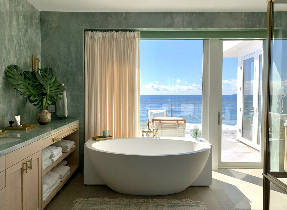 На фото: ванная комната в морском стиле с фасадами в стиле шейкер, светлыми деревянными фасадами, отдельно стоящей ванной, светлым паркетным полом, врезной раковиной, бежевым полом, зеленой столешницей, тумбой под одну раковину и подвесной тумбой