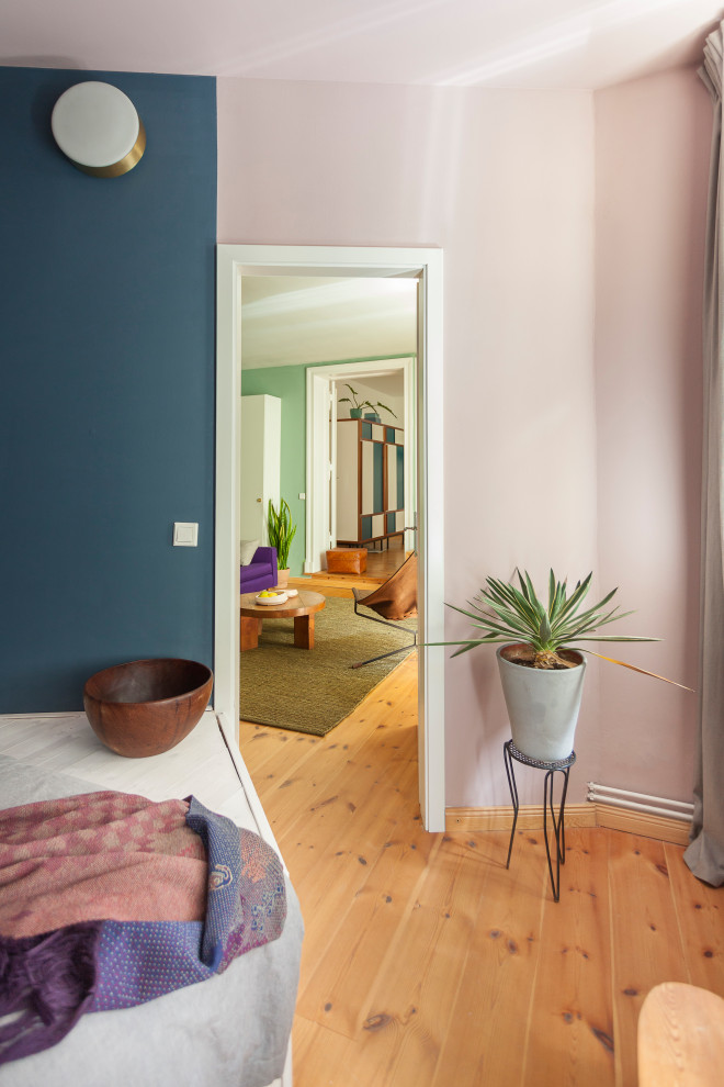 Design ideas for a large midcentury master bedroom in Berlin with pink walls and light hardwood floors.