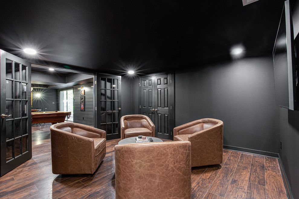 Photo of a large contemporary walk-out basement in Atlanta with a home bar, black walls, vinyl flooring, a standard fireplace, a brick fireplace surround, brown floors and tongue and groove walls.