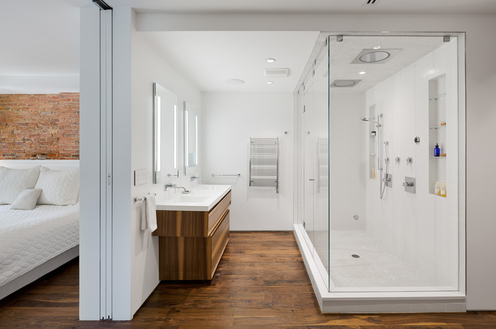 This is an example of a mid-sized contemporary master bathroom in New York with flat-panel cabinets, dark wood cabinets, a double shower, white tile, white walls, dark hardwood floors, porcelain tile and an integrated sink.