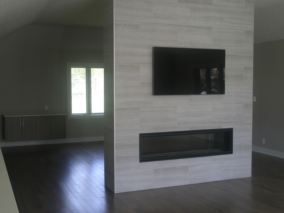 Large modern formal open concept living room in Other with grey walls, medium hardwood floors, a two-sided fireplace, a tile fireplace surround and a wall-mounted tv.