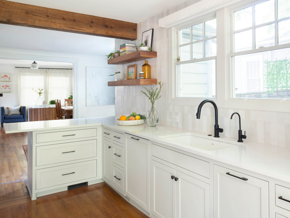 Inspiration for a small rustic kitchen/diner in Raleigh with a submerged sink, shaker cabinets, white cabinets, engineered stone countertops, white splashback, ceramic splashback, stainless steel appliances, medium hardwood flooring, a breakfast bar, brown floors and white worktops.