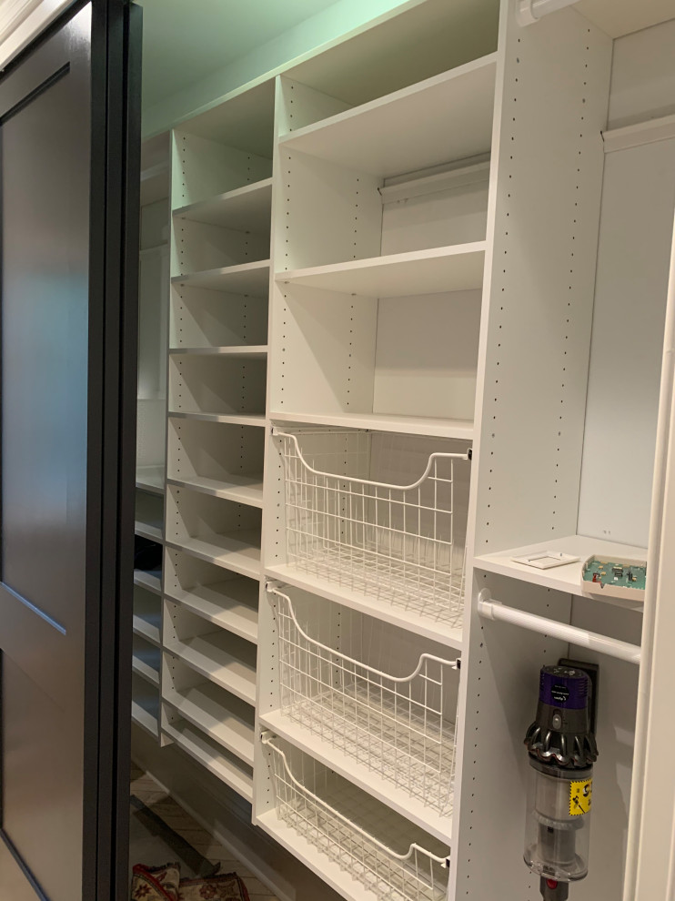 This is an example of a small transitional gender-neutral built-in wardrobe in Chicago with shaker cabinets, black cabinets, porcelain floors, beige floor and coffered.