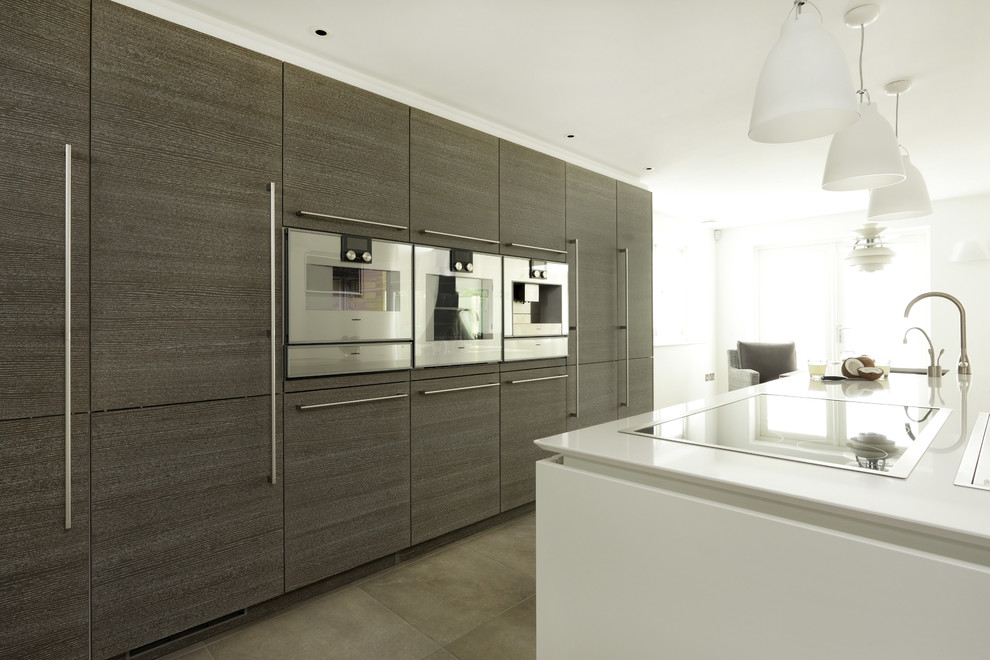 Design ideas for a large contemporary single-wall open plan kitchen in London with an integrated sink, flat-panel cabinets, dark wood cabinets, solid surface benchtops, stainless steel appliances, ceramic floors and with island.
