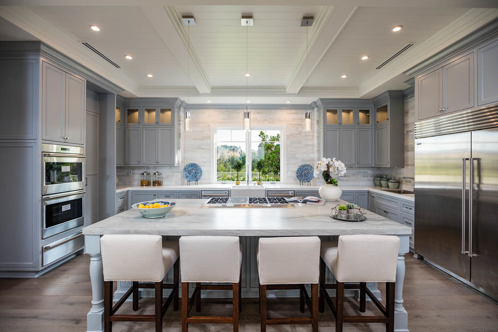 Photo of a large transitional u-shaped open plan kitchen in Los Angeles with shaker cabinets, grey cabinets, marble benchtops, beige splashback, stainless steel appliances, medium hardwood floors and with island.