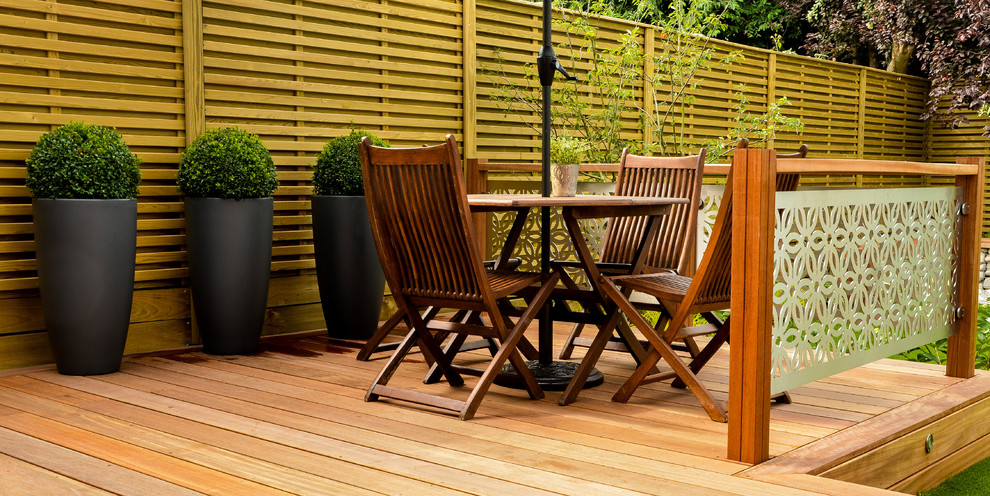 Design ideas for a mid-sized modern backyard partial sun garden for summer in London with decking.