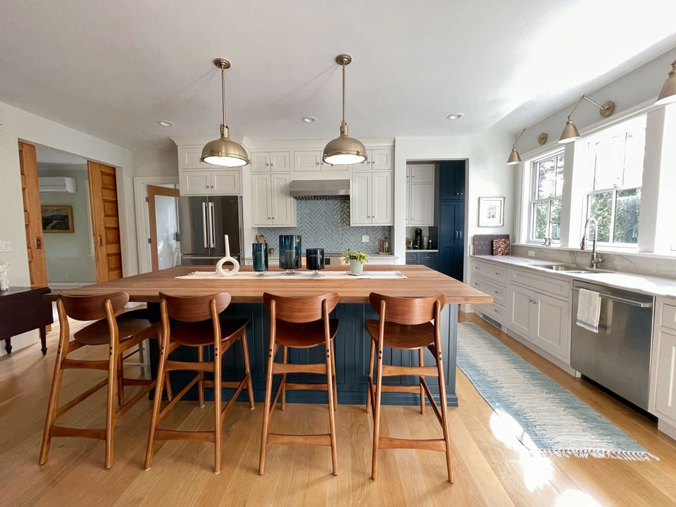 Foto på ett stort skandinaviskt vit l-kök, med en dubbel diskho, skåp i shakerstil, vita skåp, bänkskiva i kvartsit, stänkskydd i keramik, rostfria vitvaror, mellanmörkt trägolv, en köksö och blått stänkskydd