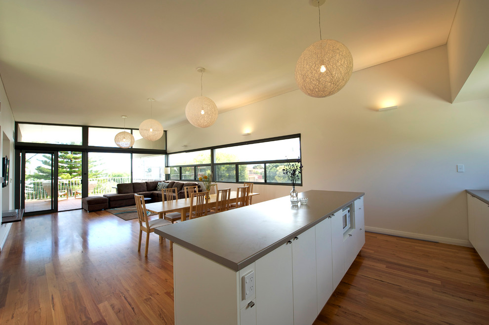 Photo of a beach style galley kitchen in Perth with flat-panel cabinets, white cabinets and medium hardwood floors.